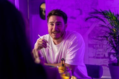 Restoranda yemek çubuklarıyla geleneksel Kore mutfağından hoşlanan ve randevuda bir kızla tartışan bir adamın portresi.