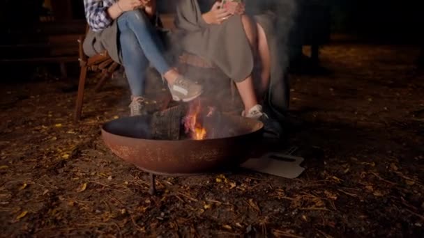 夜中に外で一緒に座っているガールフレンドのショット 火が彼らの手を暖め 木製の家の外でチャット — ストック動画
