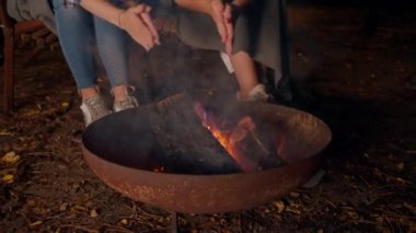 Ateşin başında birlikte oturan, ellerini ısıtan ve ahşap evlerinin önünde sohbet eden kız arkadaşları.