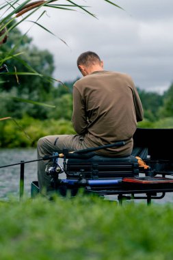 Balıkçı oltayla ya da dönen aletlerle nehir kıyısında dikiz aynasından balık tutar.