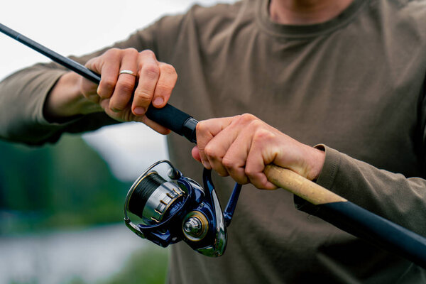 close-up Fly fisherman male hands with fishing rod spinning in hands feeder free style method