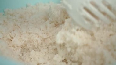 Bir suşi şefinin suşi kaşığıyla pirinç alırken yılan balığı ve somon balığının arka planına karşı suşi hazırladığı yakın plan.