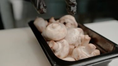 Profesyonel bir mutfak masasında, siyah plastik bir tepside mantar yakın plan suşi hazırlama sürecinde.