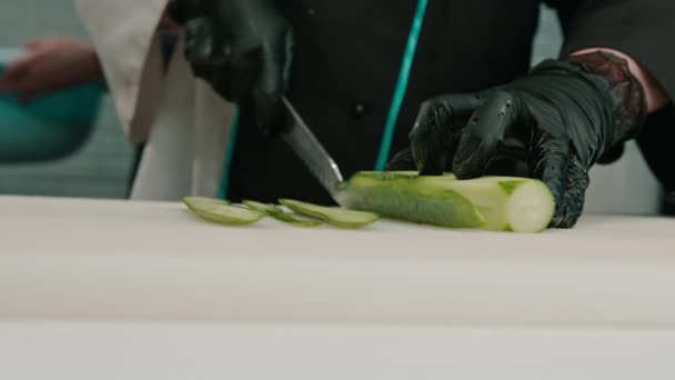 Close Van Een Sushi Maker Handschoenen Snijden Van Een Komkommer — Stockvideo