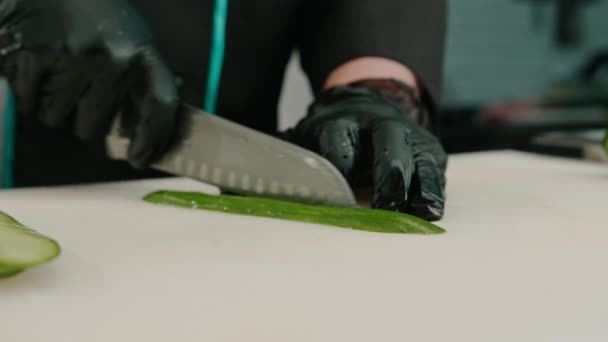 Κοντινό Πλάνο Ενός Κατασκευαστή Σούσι Γάντια Που Κόβει Ένα Αγγούρι — Αρχείο Βίντεο