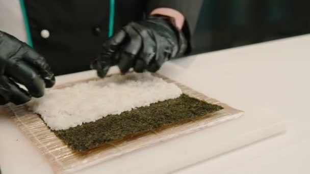 黒い手袋の寿司シェフのクローズアップ 米の海老シートを使用して寿司を準備する エビのフィレットエビのカルドチーズキュウリのアボカド キッチンテーブル — ストック動画