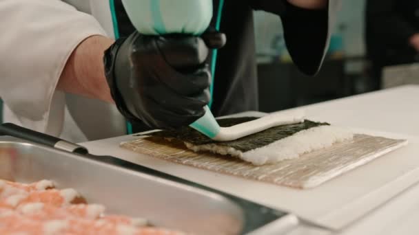 黒い手袋の寿司シェフのクローズアップ 米の海老シートを使用して寿司を準備する エビのフィレットエビのカルドチーズキュウリのアボカド キッチンテーブル — ストック動画