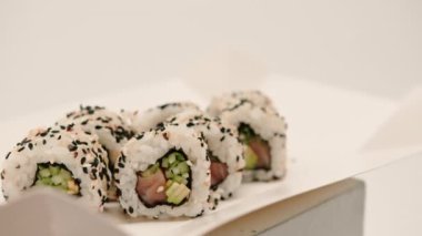 Salatalık mango pilavı ve beyaz arka planda susam olan somonlu bir rulo yakın çekim.