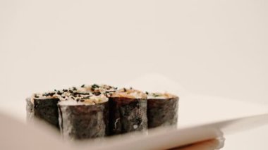 Suşi kutusunda soya soslu avokadoyla maki rulosunu yakın plan beyaz arka plan