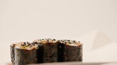 Suşi kutusunda soya soslu avokadoyla maki rulosunu yakın plan beyaz arka plan