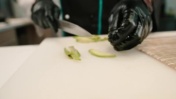 Detailní Záběr Sushi Výrobce Rukavicích Řezání Avokádo Profesionálním Kuchyňským Nožem — Stock video