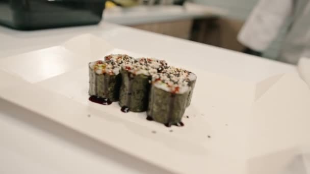 うさぎソースに浸し 寿司屋のキッチンでゴマの種をまき散らしたアボカドのメイロールのクローズアップ — ストック動画