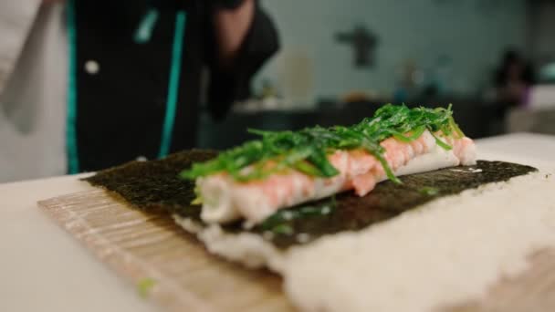 寿司シェフはサーモンで美味しいエビロールを用意し 竹寿司マットにチカウエイドをツイスト — ストック動画