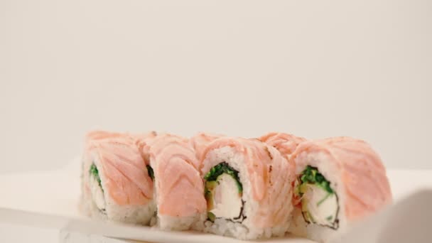在寿司送货箱的白色背景上放上烤鲑鱼 黄瓜和奶酪的面包卷的特写 — 图库视频影像