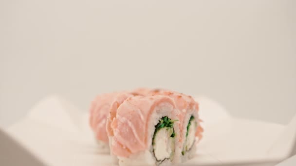 Detail Role Pečeným Lososem Okurkou Sýrem Bílém Pozadí Krabici Sushi — Stock video