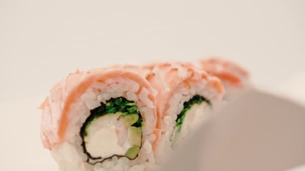 Zbliżenie Bułki Pieczonym Łososiem Ogórkiem Serem Białym Tle Pudełku Sushi — Wideo stockowe