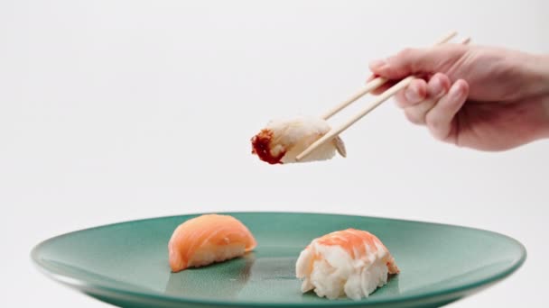 箸を使って男性の手を閉じ サーモンとエビの寿司を白い背景に一枚のウナギの寿司を取る — ストック動画