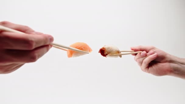 白い背景にウナギ寿司とサーモン寿司を抱える箸で男性の手を閉じる — ストック動画