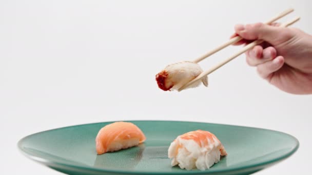 箸を使って男性の手を閉じ サーモンとエビの寿司を白い背景に一枚のウナギの寿司を取る — ストック動画