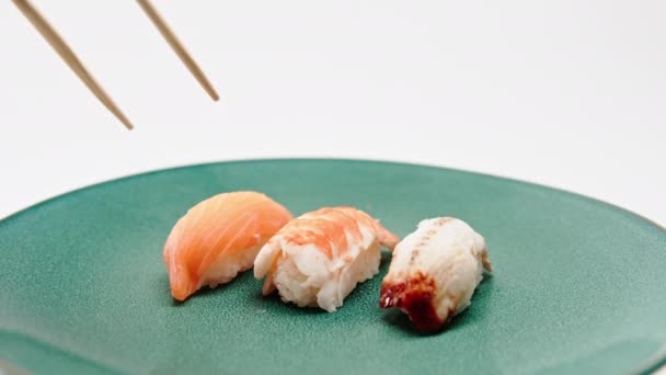 白い背景にウナギ寿司とサーモン寿司を抱える箸で男性の手を閉じる — ストック動画