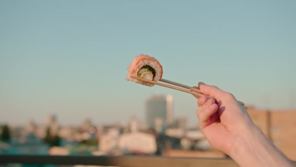 在天空的背景下 男人们拿着筷子在夏天的阳台上吃着美味的新鲜寿司 — 图库视频影像