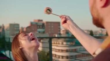 Terasta yemek çubuklarıyla lezzetli bir suşi tutan bir adamın kız arkadaşını beslediği yakın plan.