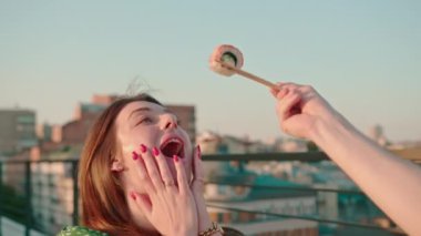 Terasta yemek çubuklarıyla lezzetli bir suşi tutan bir adamın kız arkadaşını beslediği yakın plan.