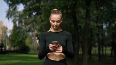 Spor giysili bir kızın parkta sokakta konuşurken dikkatli bir şekilde çekilmiş fotoğrafı.