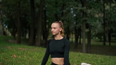 Genç ve güzel bir kız, sabah antrenmandan sonra parkta etkin bir hayat sürüyor.