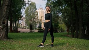 Genç ve güzel bir kız, sabah antrenmandan sonra parkta etkin bir hayat sürüyor.