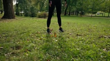 Sportif bir kız sabah egzersizleri sırasında kulaklıkla müzik dinlerken omuzlarını ve boynunu uzatıyor.