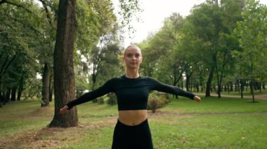 Spor kızı, antrenmandan önce kollarını omuz eklemlerini ısıtarak dairesel hareketler yapar.