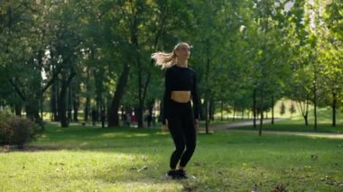 Yeşil yaz parkındaki eğitimden önce atlama egzersizleri yapan bir kız sporcu kız.