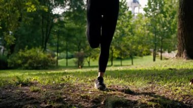 Bacaklarını esneten kadın bacaklarının yakın çekimi sabah parkta antrenman yaparken yeşil çimenleri esnetiyor.