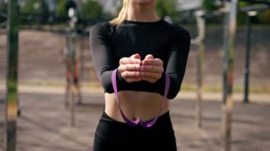 Lastik bantlarla egzersiz yapan bir kızın yakın plan çekimi sokakta çalışırken kol kaslarını güçlendirir.