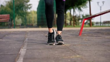 Spor sahasındaki kasları güçlendirmek için elastik bir bantla egzersiz yapan kız spor eğitmeninin Legs 'ine yakın plan.