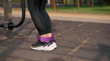 Legs of Legs 'in spor eğitmeninin spor sahasındaki kasları güçlendirmek için elastik bir bantla egzersiz yaptığı yakın plan.