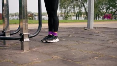 Legs of Legs 'in spor eğitmeninin spor sahasındaki kasları güçlendirmek için elastik bir bantla egzersiz yaptığı yakın plan.