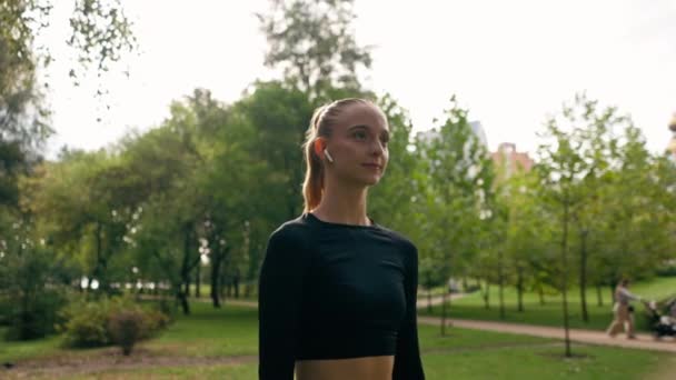 一名身穿运动服的女孩在公园室外训练前 在热身过程中进行圆形肩部运动 — 图库视频影像