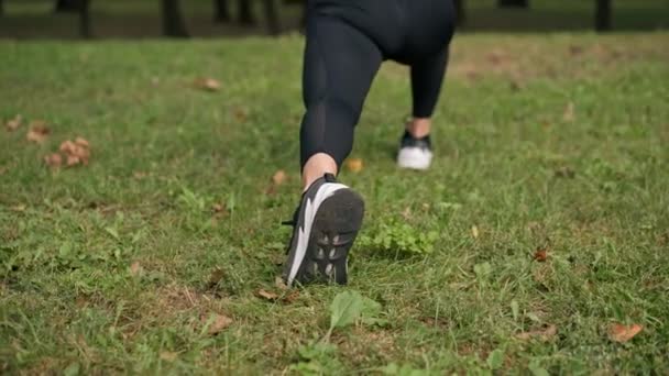 スポーツウェアの若い女の子の足のクローズアップ 肺トレーニングバランスを行い 太い筋肉の後ろのビューを伸ばす — ストック動画