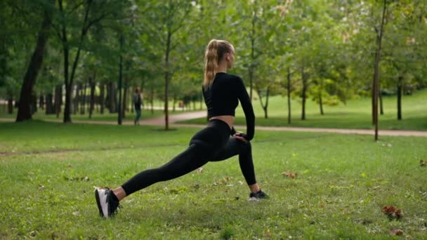 スポーツウェアの若い女の子は バランスを訓練し 背中のビューを伸ばすためにラウンジエクササイズを行います — ストック動画