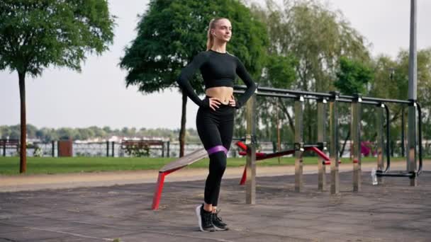 Красивая Девушка Спортивной Форме Выполняет Упражнения Накачать Ноги Резиновой Лентой — стоковое видео