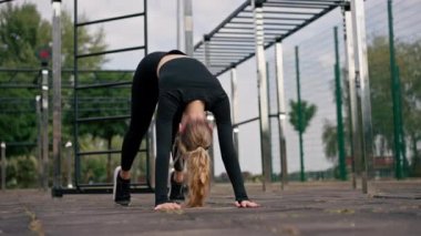 Bir kız aktif spor sahası aktif yaşam tarzından sonra sırtını germek için tahta egzersizi yapıyor.