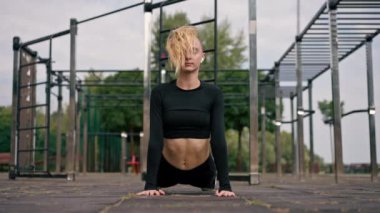 Bir kız aktif spor sahası aktif yaşam tarzından sonra sırtını germek için tahta egzersizi yapıyor.