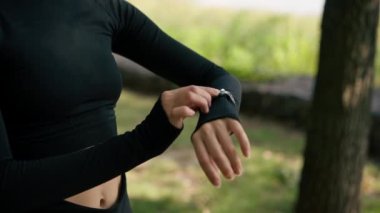 Kaç kilometre koştuğunu belirlemek için elinde spor saatine bakan bir kızın yakın çekimi.