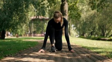 Profesyonel bir kız sporcu, parkta aktif bir yaşam tarzında sabah antrenmanı sırasında hız yarışına hazırlanır.