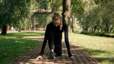 Profesyonel bir kız sporcu, parkta aktif bir yaşam tarzında sabah antrenmanı sırasında hız yarışına hazırlanır.