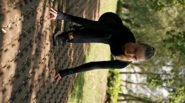 Dikey video: Profesyonel bir kız sporcu parkta aktif bir yaşam tarzında sabah antrenmanı sırasında hız yarışına hazırlanıyor