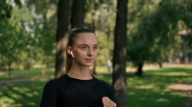Aktif bir sabah koşusundan sonra atletik genç kadın parktaki sokakta şişeden su içiyor.