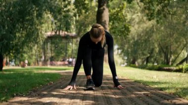 Profesyonel bir kız sporcu, parkta aktif bir yaşam tarzında sabah antrenmanı sırasında hız yarışına hazırlanır.